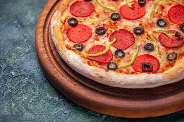 橄榄美味的比萨饼在左边的木制砧板上 在孤立的黑暗表面上 在特写镜头中有自由空间西红柿左板