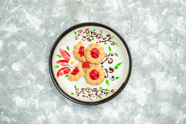 容器顶视图美味饼干与红色果冻内板上的白色背景蛋糕饼干甜茶容器蛋糕饼干