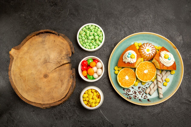 餐厅顶视图美味的馅饼片与橘子和糖果的深灰色背景水果糖果蛋糕馅饼面团茶顶糖果盘子