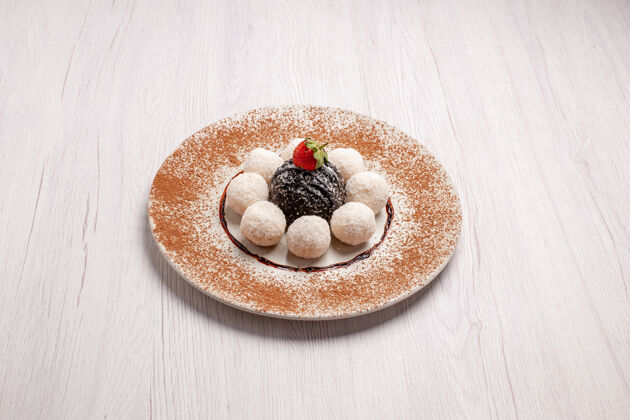 甜点正面是美味的椰子糖和巧克力蛋糕在白色空间容器糖草莓