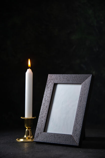 黑暗前视图白色蜡烛与相框上的黑暗火燃烧打蜡