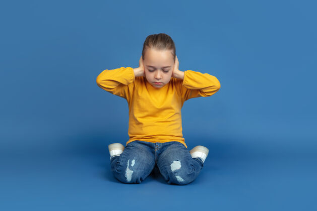 表情孤独地坐在蓝色工作室背景上的悲伤小女孩的肖像自闭症的感觉现代问题 社会问题的新视野自闭症的概念 童年 医疗保健 医学情绪孤独孤独
