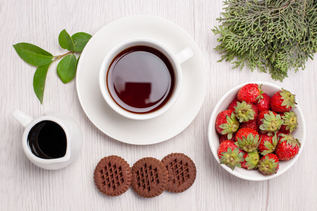 饼干顶视图一杯茶加饼干和草莓放在白桌子上糖茶饼干饼干甜草莓食物茶碟