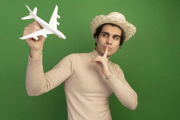 沉默高兴的年轻帅哥穿着韩服 抬头看着玩具飞机 在绿色的墙上显示出沉默的姿态穿姿势手势