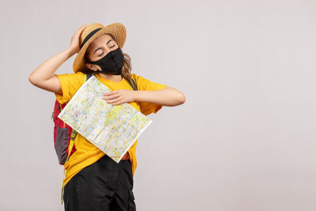人前视图年轻女子背着背包拿着地图闭上眼睛人流行面具