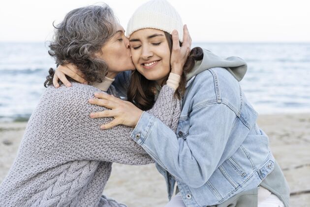 债券妈妈和女儿在沙滩上度过了一个温柔的时刻亲吻水平女人