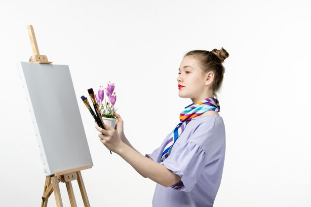 花正面图女画家在白墙上画花朵画画家画架铅笔画女人正面视图画架