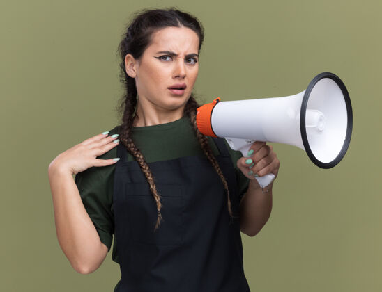 表情年轻的女理发师穿着制服 手放在肩膀上 隔着橄榄绿的墙 用扩音器讲话喇叭脸理发师