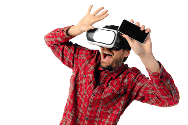 电话年轻的白人男子情感游戏 使用虚拟现实耳机和智能手机隔离在白色工作室背景下现代科技概念 小玩意 技术 人类情感 广告空间年轻手机虚拟现实