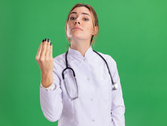 表演年轻的女医生穿着医用长袍 听诊器在绿色的墙上显示着孤立的尖端姿势姿势提示听诊器