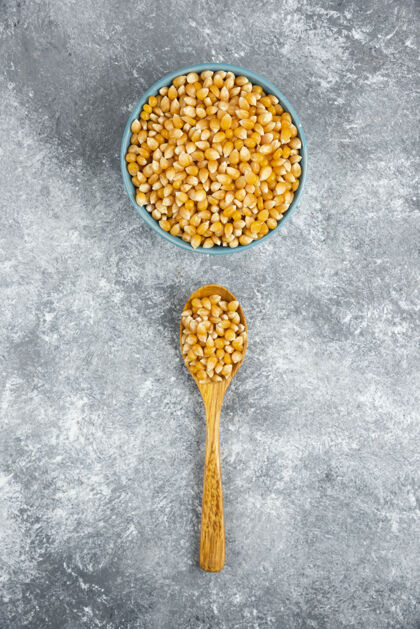 谷物一堆生玉米种子放在蓝色的碗里和木勺里自然玉米碗