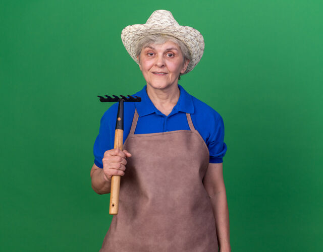 印象印象深刻的上了年纪的女园丁戴着园艺帽拿着耙子举行耙子园艺