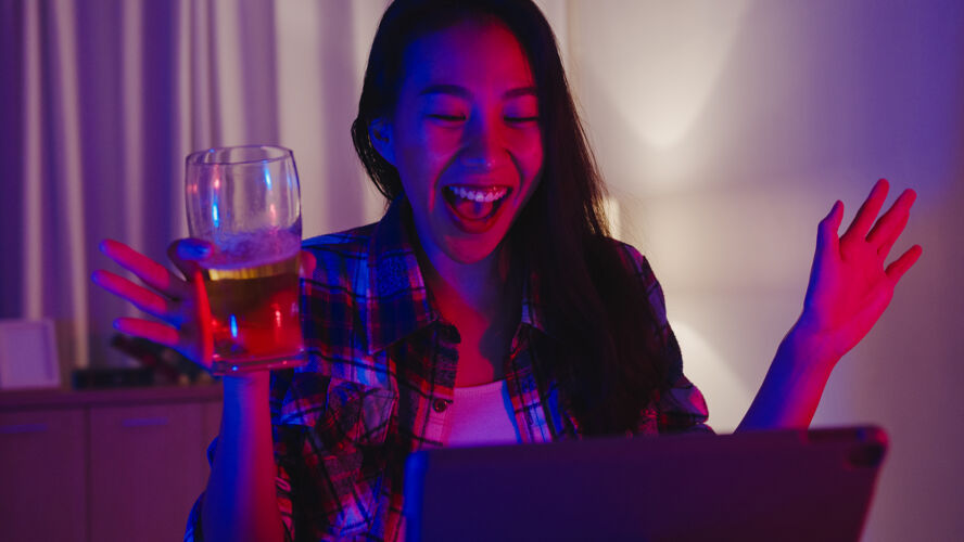 隔离年轻的亚洲女士喝啤酒玩得开心快乐的一刻迪斯科霓虹夜总会活动在线庆祝通过视频电话在客厅在家里酒精会议女性