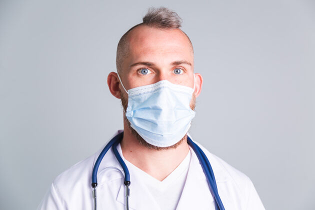 流感灰色墙上的帅哥医生 脸上戴着医用防护面具拇指防护疾病