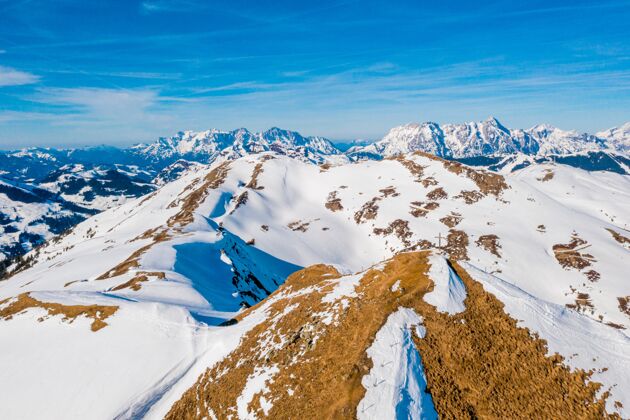 奥地利美丽的拍摄雪域覆盖的阿尔卑斯山与十字架上的一座山峰下的蓝天景观十字架度假村