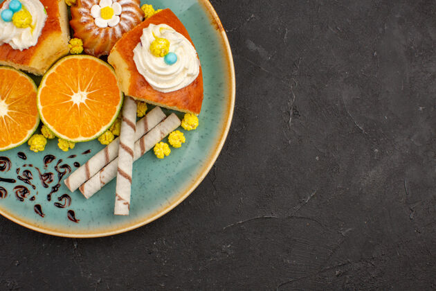 盘子顶视图美味的蛋糕片与烟斗饼干和橘子片深色背景水果蛋糕派饼干甜茶餐茶食物