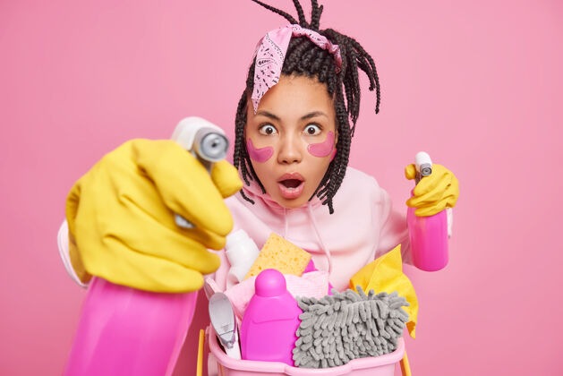 家务男人带着omg表情看着拿着清洁用品准备打扫房间进行美容程序 同时在室内摆出粉色的姿势手套海绵家庭