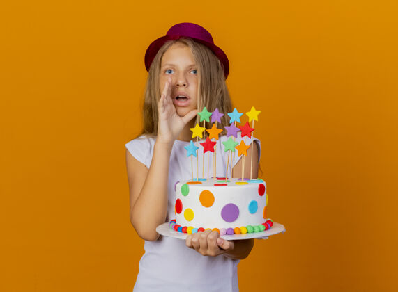 电话漂亮的小女孩戴着节日帽子拿着生日蛋糕看着惊讶的叫人 生日派对的概念女孩橘子生日