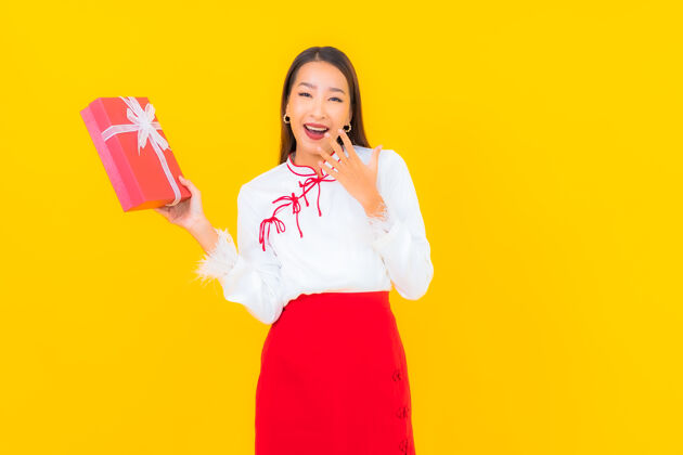 快乐肖像美丽的亚洲年轻女子与红色礼盒黄色年轻韩国幸运
