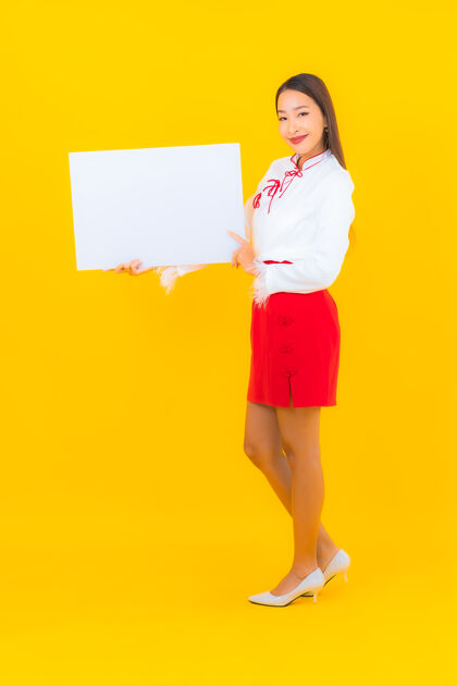 成人肖像美丽的亚洲年轻女子在黄色的广告牌上展示白色的空广告公告牌注意展示