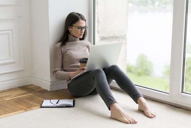 年轻人坐在地板上操作笔记本电脑的女人在线房子室内