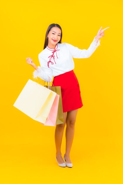 客户一位年轻漂亮的亚洲女士 手拿购物袋 信用卡 黄色购物狂肖像交易