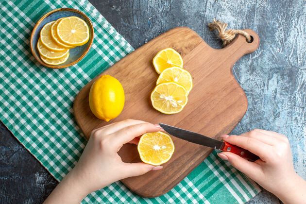 健康俯视图上的手切碎新鲜柠檬在木制砧板上黑暗的背景背景健康可食用水果