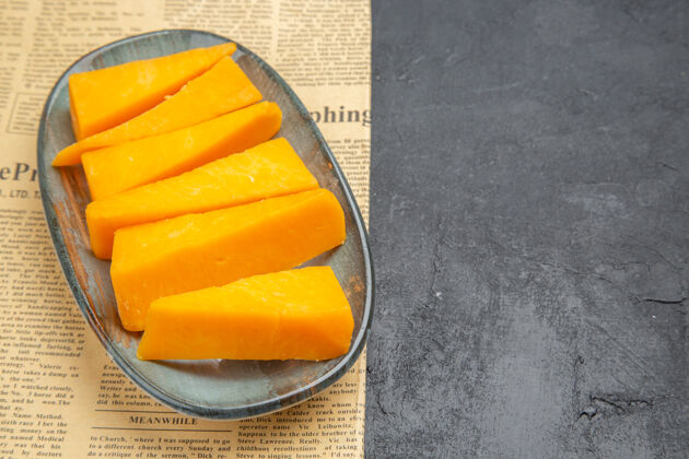 可食用的水果上图：一张旧报纸上蓝色盘子上新鲜的黄色切片奶酪盘子食物甜点