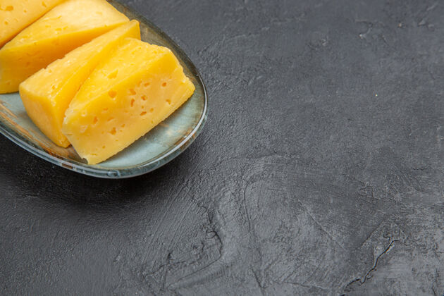 可食用水果半张美味的黄色切片奶酪放在右边的蓝色盘子里 黑色背景农产品美味背景