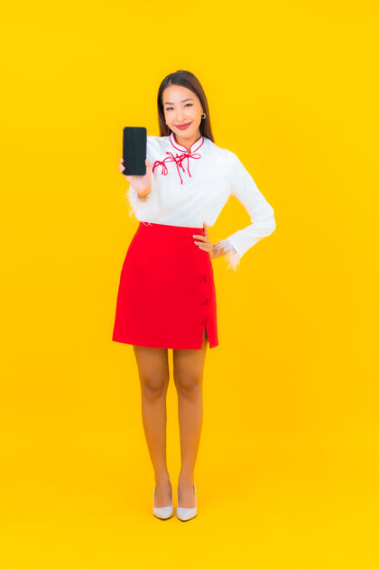 技术用黄色的智能手机描绘美丽的亚洲年轻女子设备青少年手