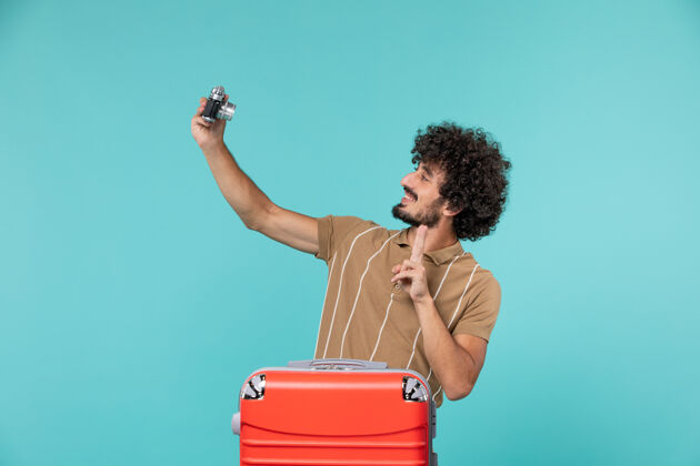 行李带着大红色手提箱的度假男人用蓝色的相机拍照肖像旅行成人