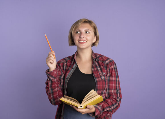 斯拉夫微笑着的年轻斯拉夫学生女孩拿着铅笔和书看着身边紫色铅笔举行