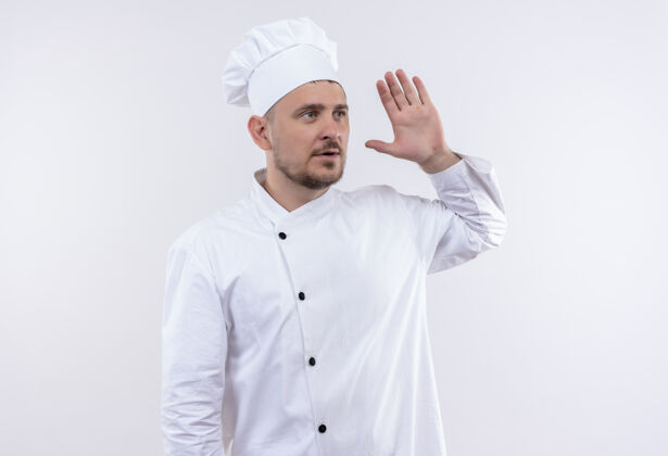 厨师年轻帅气的厨师穿着厨师制服 抬起手 孤立地站在白色的墙上 看着一旁 给人留下了深刻的印象年轻手烹饪