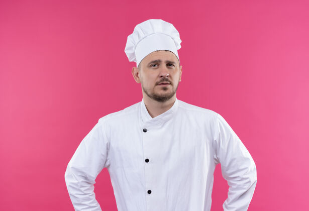 厨艺自信的年轻帅哥厨师身着厨师制服孤立在粉红色的墙上年轻厨师自信
