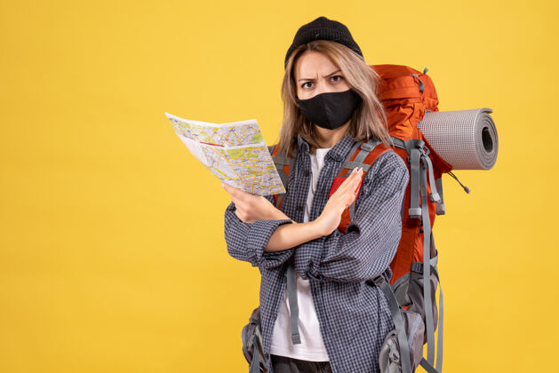 女士带着黑色面具和背包拿着地图的旅行女孩肖像时尚面具