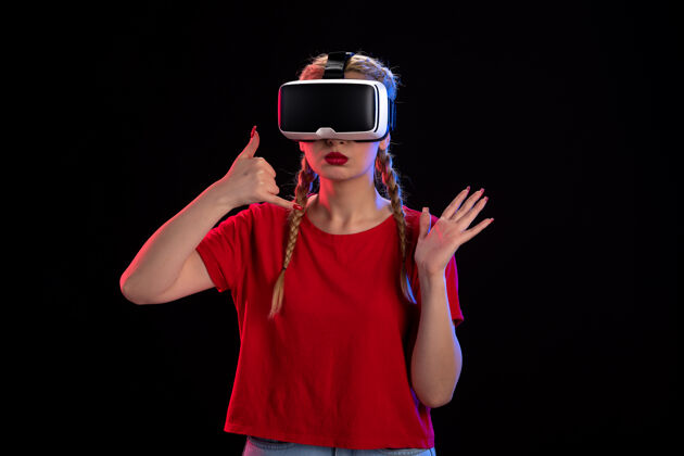 肖像在黑暗的墙壁上玩虚拟现实的年轻女性的正面视图现实游戏年轻女性