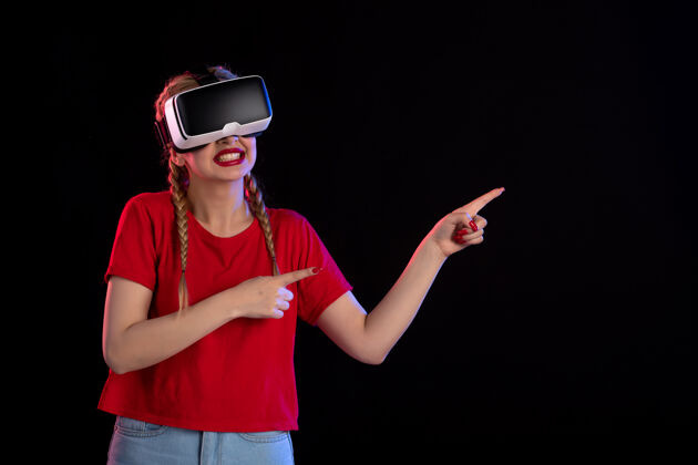虚拟现实年轻女性在黑暗的墙上玩虚拟现实的正面图姿势视图视觉
