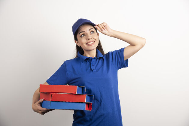 工人年轻的女信使拿着一纸板披萨和剪贴板盒子剪贴板制服