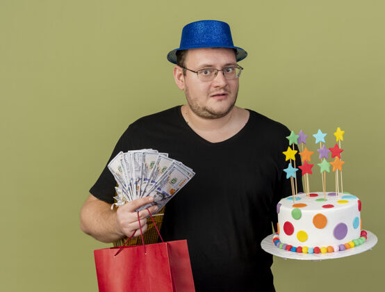 复制焦急的成年斯拉夫人戴着眼镜 戴着蓝色派对帽 手里拿着钱礼盒 纸购物袋和生日蛋糕帽子聚会空间