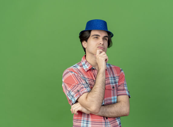 男人体贴英俊的白种人 戴着蓝色的派对帽 托着下巴看着身边壁板举行下巴