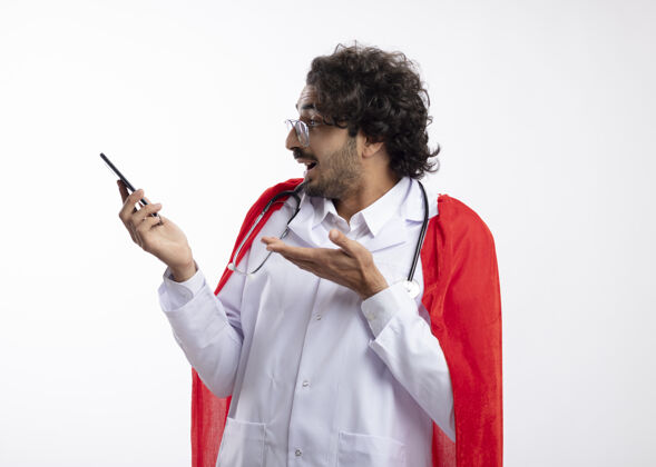 太空一个戴着眼镜 身穿医生制服 身穿红色斗篷 脖子上戴着听诊器的年轻白种人惊讶地看着电话男人眼镜副本