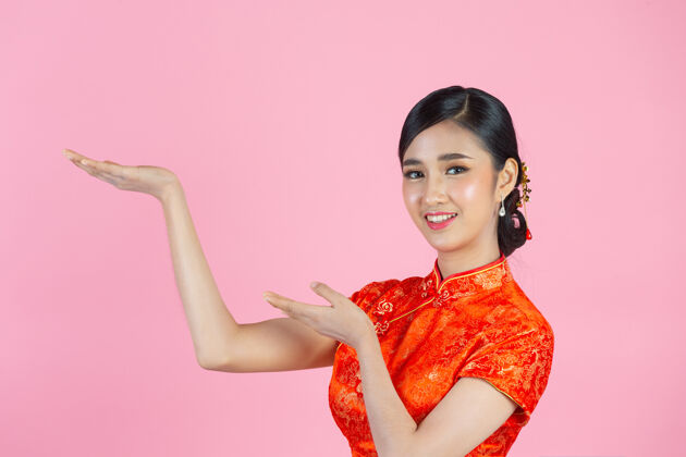 微笑美丽的亚洲女人快乐的微笑 在中国新年的粉红色背景上向你展示一些东西中国人文化女孩