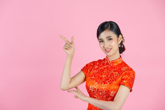 新美丽的亚洲女人快乐的微笑 在中国新年的粉红色背景上向你展示一些东西女性空虚欢呼