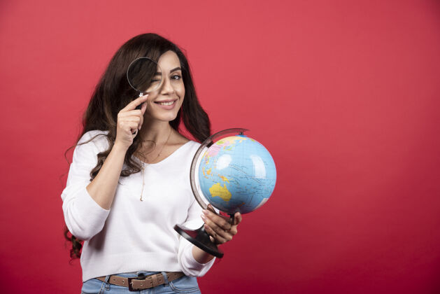 肖像年轻女子拿着地球仪 用放大镜看高质量的照片工作聪明地球仪