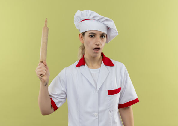 厨师年轻漂亮的厨师穿着厨师制服 手拿擀面杖孤立地站在绿色的墙上印象烹饪年轻