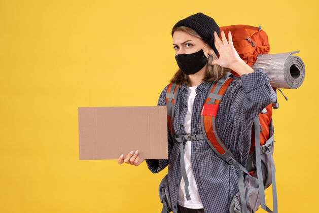 东西带着黑色面具和背包拿着纸板的旅行女孩在听什么面具成人女孩旅行者