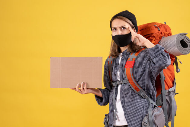 人体贴的旅行女孩 戴着黑色面具 背着硬纸板的背包脸纸板表情