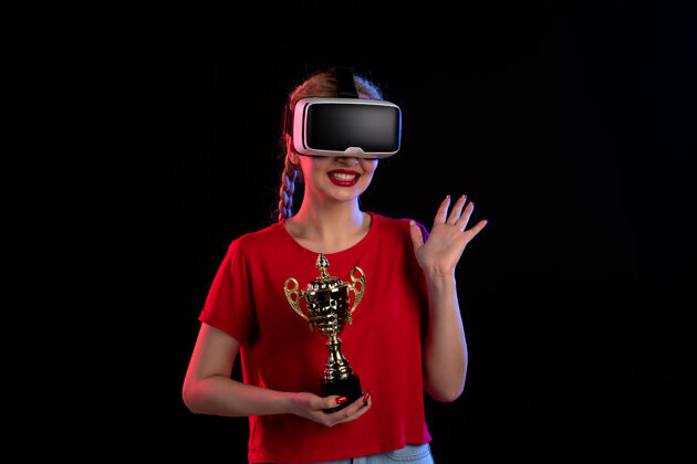 虚拟现实在黑暗的墙壁上 年轻女性正在玩虚拟现实和冠军杯视图人物年轻女性