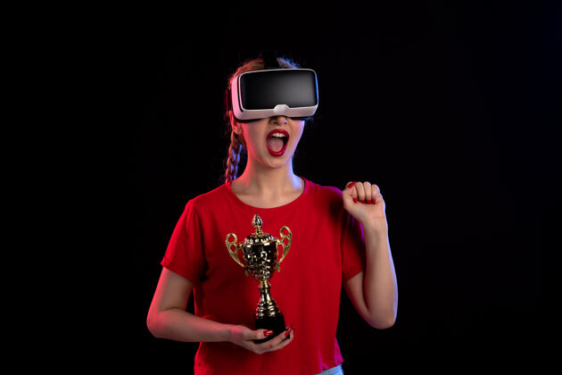 正面在黑暗的墙壁上 年轻女性正在玩虚拟现实和冠军杯成人肖像游戏