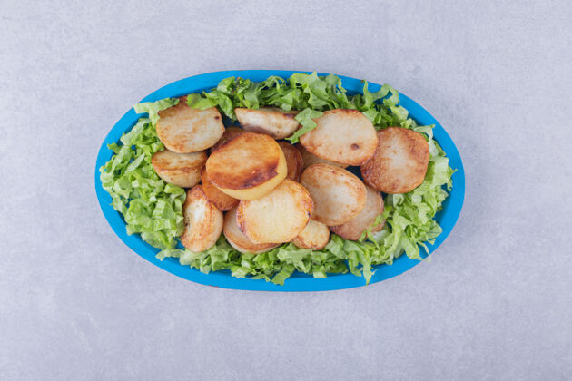 脆蓝盘子上的炸土豆和生菜烹饪圆料理